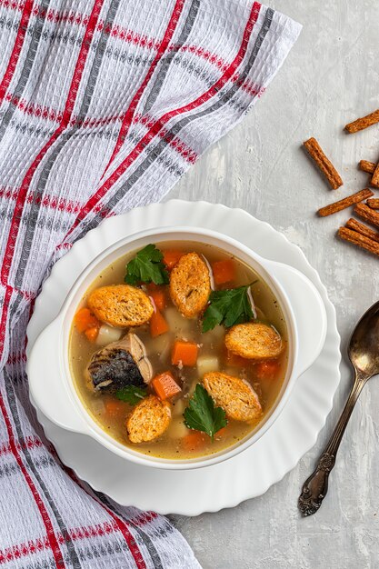 Sopa de peixe em conserva preparada na hora com biscoitos em um fundo de concreto com ervas