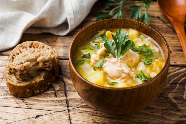 Sopa de peixe em uma tigela de madeira com ervas frescas.