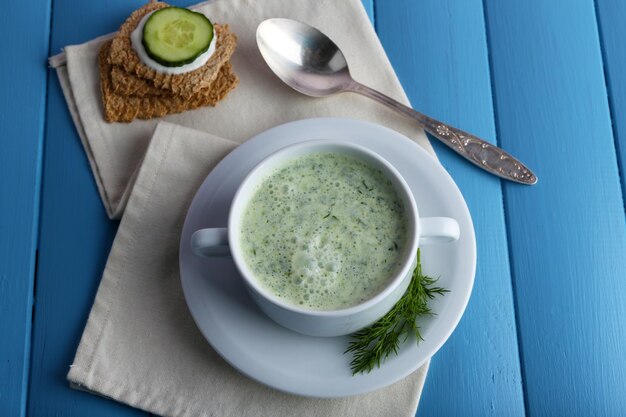 Sopa de pepino em uma tigela em um fundo de tábuas de madeira coloridas