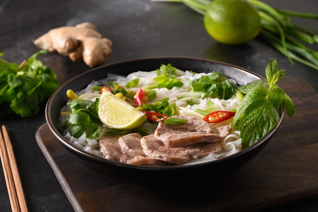 Sopa de pho bo com carne na tigela na cozinha vietnamita de fundo preto