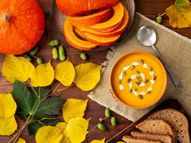 Sopa de purê de abóbora de comida de outono deixa vista de mesa de madeira velha marrom escura