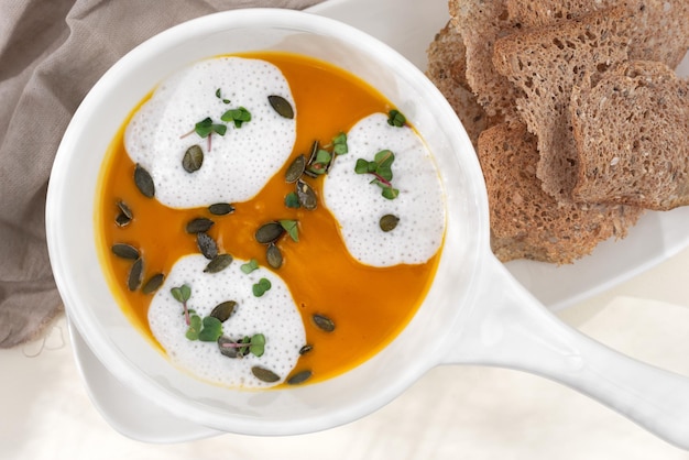 Sopa de purê de abóbora doce com creme de coco no fundo branco