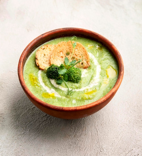 Sopa de purê de brócolis com bolachas e legumes frescos nas mesas cozinha caseiracomida vegetariana