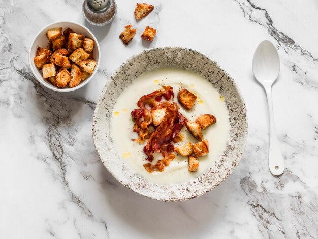 Sopa de purê de couve-flor com bacon e bolachas em uma vista superior de fundo de mármore Delicioso conceito de comida de conforto