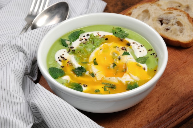 Sopa de purê de ervilha com ovo escalfado, creme de leite, folhas de hortelã temperadas com especiarias.