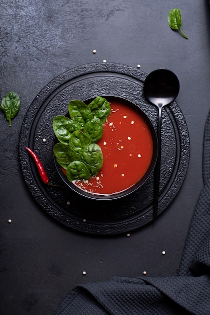 Sopa de purê de tomate com espinafre em uma tigela preta, vista de cima