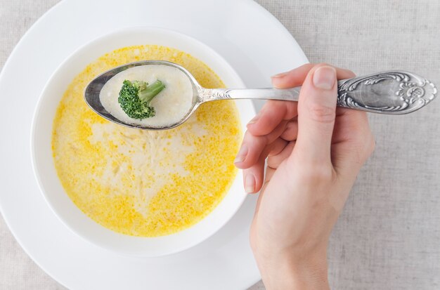 Sopa de queijo com brócolis em um prato branco sobre uma toalha de mesa de linho branco