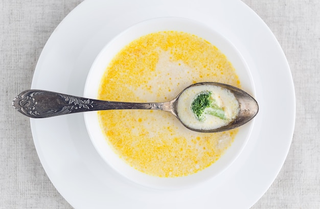 Sopa de queijo com brócolis em um prato branco sobre uma toalha de mesa de linho branco