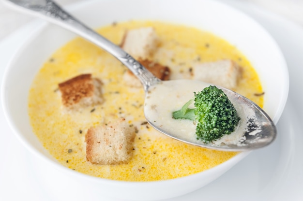 Sopa de queijo com brócolis em um prato branco sobre uma toalha de mesa de linho branco