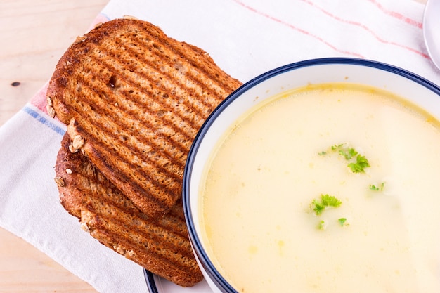 Sopa de queijo em um prato branco com pão torrado