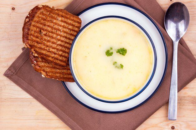 Sopa de queijo em um prato branco com pão torrado