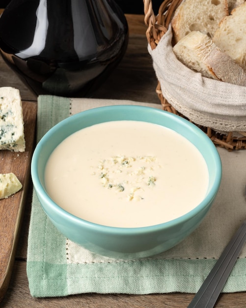 Sopa de queijo em uma tigela com fatias de pão e vinho sobre a mesa de madeira