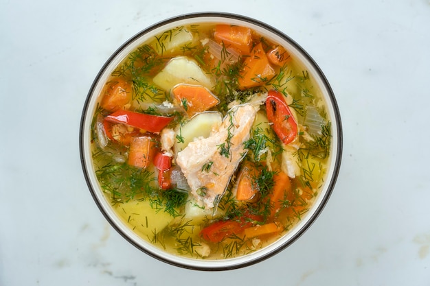 Sopa de salmão com batata, cenoura, endro e pimenta na tigela, close-up