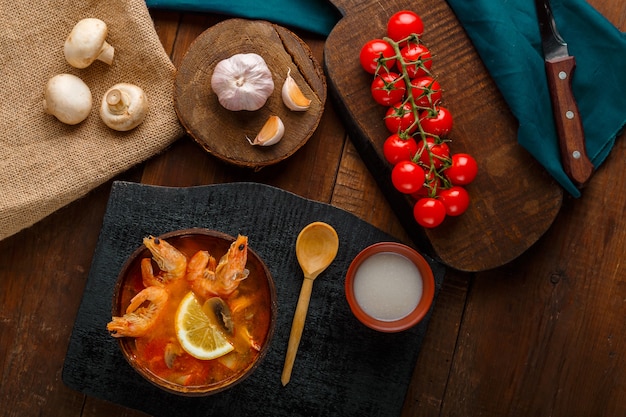 Sopa de tom inhame com camarão e leite de coco em uma mesa em um quadro negro e uma colher. Foto horizontal