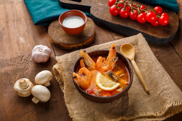 Sopa de tom inhame com camarão e leite de coco na mesa em um guardanapo de linho ao lado de legumes e uma colher. Foto horizontal