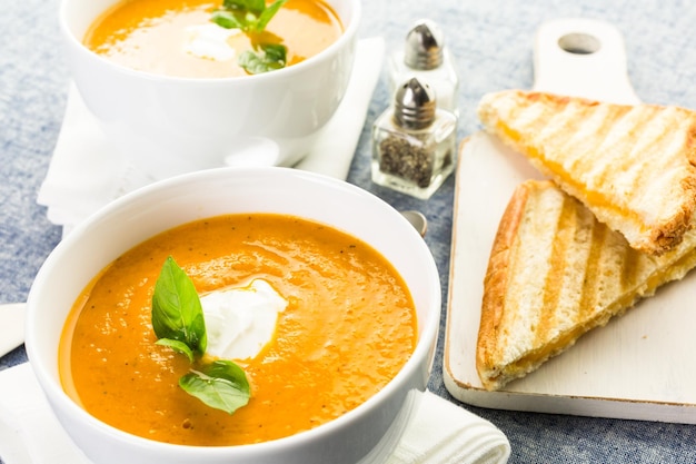 Sopa de tomate assada cozida com tomates orgânicos da herança e servida com sanduíche de queijo grelhado.