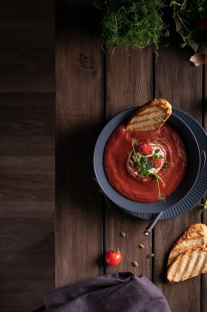 Sopa de tomate caseiro em uma tigela azul com torradas de pão em uma mesa de madeira