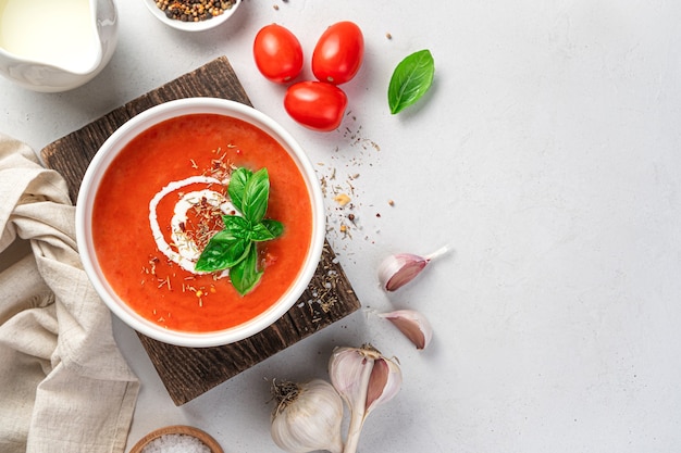 Sopa de tomate com creme e manjericão fresco em um fundo cinza