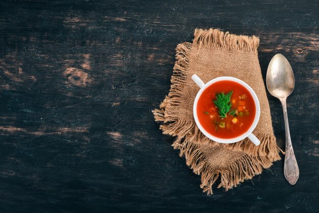 Sopa de tomate com pimentão e legumes comida saudável em um fundo preto de madeira vista superior copie o espaço para o seu texto