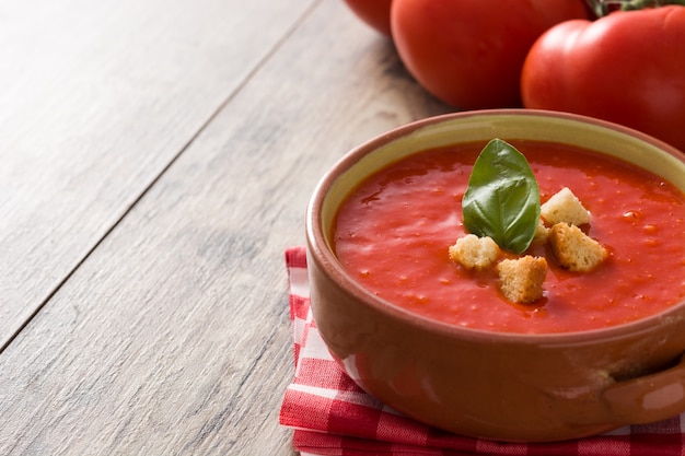 Foto sopa de tomate em uma tigela marrom na mesa de madeira. copie o espaço