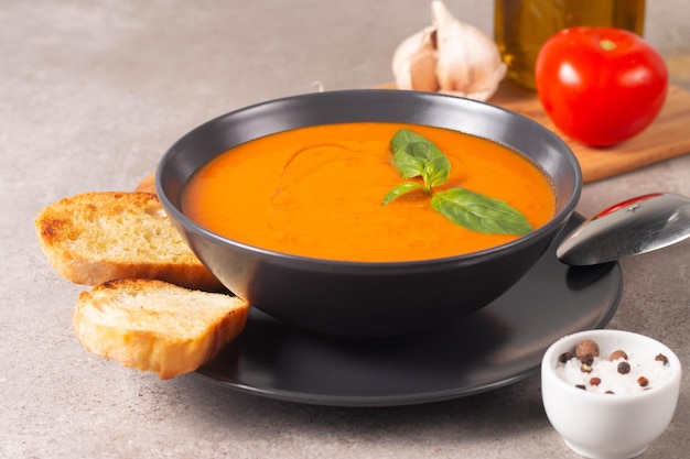 Sopa de tomate fresca e saudável com manjericão pimenta alho tomate e pão em fundo de madeira