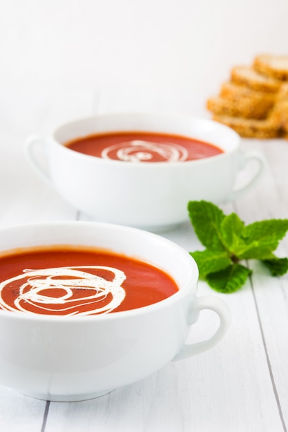 Sopa de tomate fresco em copo branco na mesa de madeira branca