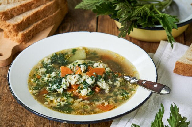 Sopa de urtiga com legumes e ovos em uma tigela branca