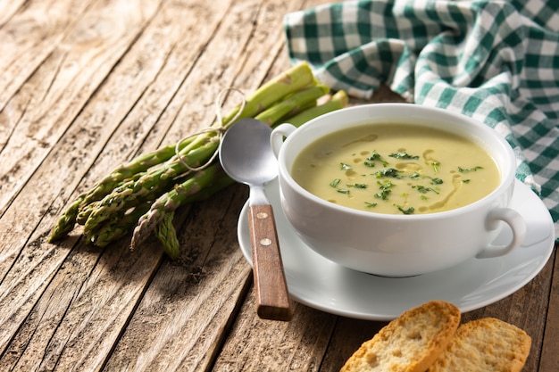 Sopa de espárragos verdes frescos en la mesa de madera