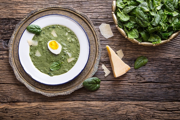 Sopa de espinacas. Porción de sopa de espinacas con huevo y queso parmesano en estilo retro.