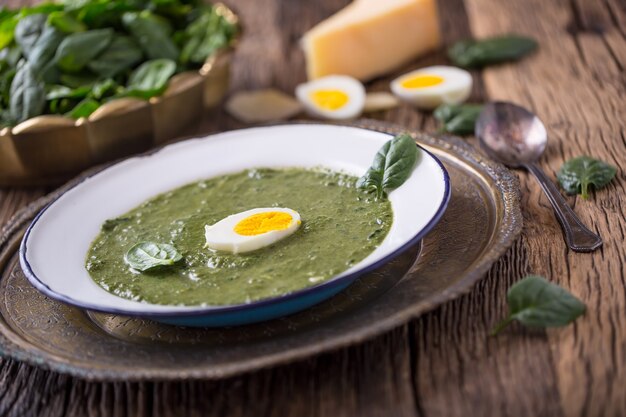 Sopa de espinacas. Porción de sopa de espinacas con huevo y queso parmesano en estilo retro.