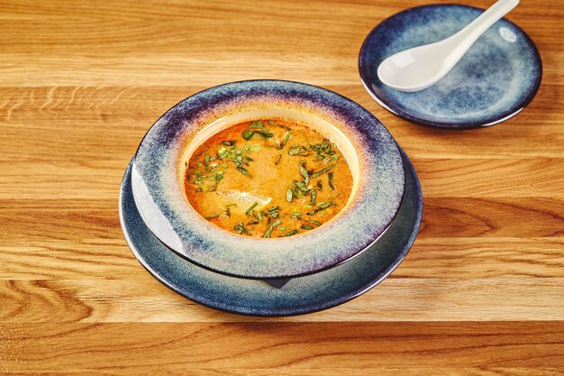 Sopa de estilo asiático Tom Yum en un tazón sobre una mesa de madera