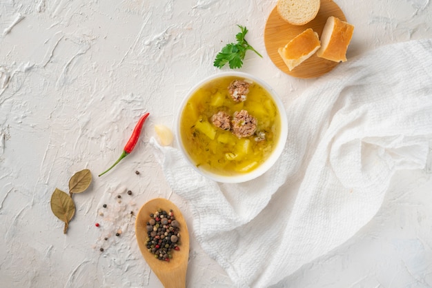 Sopa fervida fresca quente com almôndegas e batata com pão em uma mesa branca, jantares saborosos