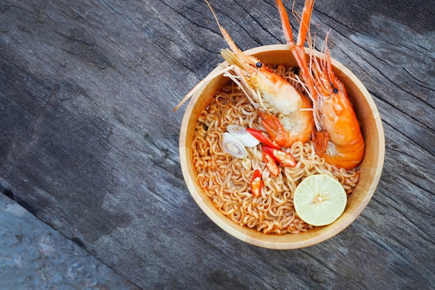 Sopa de fideos instantánea picante con camarones en un tazón de madera sobre fondo de madera