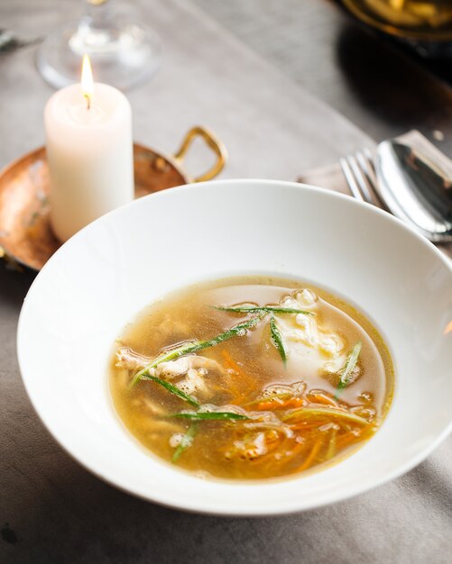 Foto sopa de fideos de pollo casera con verduras en una placa blanca.