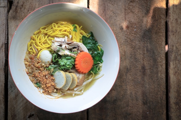 Sopa de fideos tailandesa amarilla con pollo y bola de pescado y zanahoria en un tazón