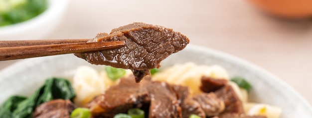 Sopa de fideos con ternera comida famosa taiwanesa en un bol sobre una mesa de madera