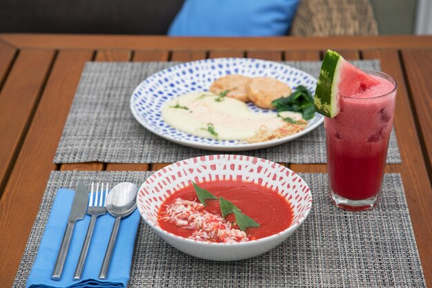 Sopa fria de comida e tomate em uma mesa de madeira com radsih de batata de pepino de beterraba