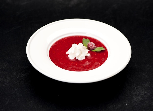 Sopa fría con fresas y frambuesa o batido en un bol sobre fondo negro