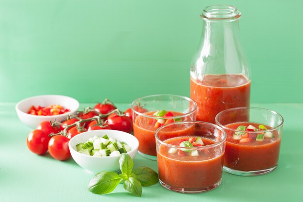 Sopa fría de gazpacho en vidrio e ingredientes.