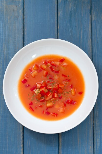 Sopa fría de tomate en superficie de madera azul