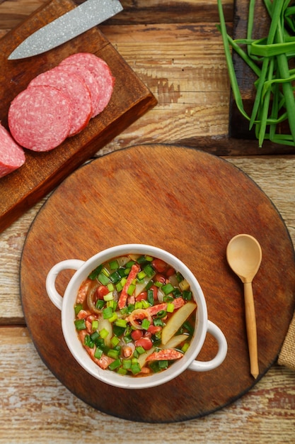 Sopa de frijoles de la cocina judía cholit en un puesto redondo cerca de los ingredientes del pan y una cuchara de madera