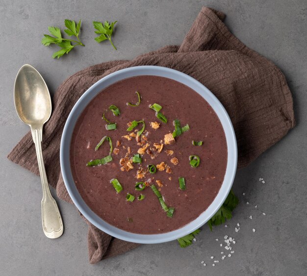 Sopa de frijoles negros en un bol con condimentos sobre fondo de piedra