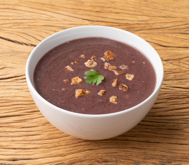 Sopa de frijoles negros en un bol sobre una mesa de madera