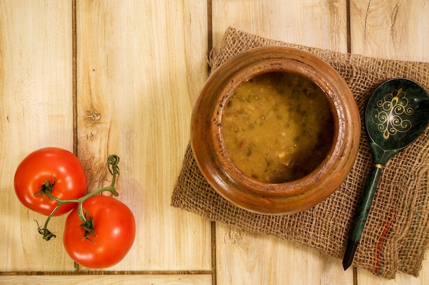 Sopa de frijoles en una olla tradicional en un piso de madera.