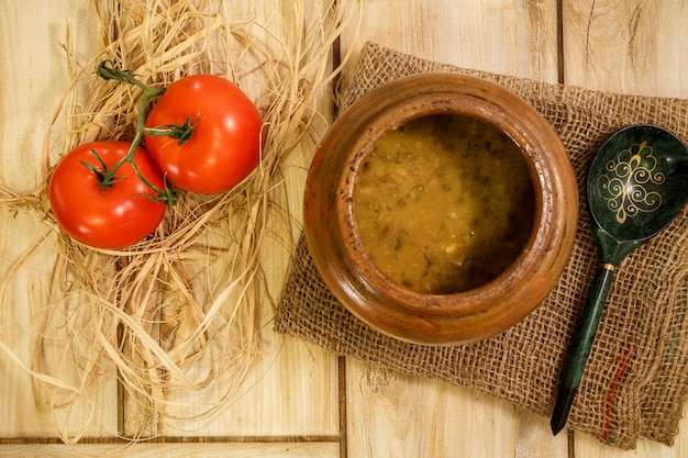 Sopa de frijoles en una olla tradicional sobre una mesa de madera. Vista desde arriba.