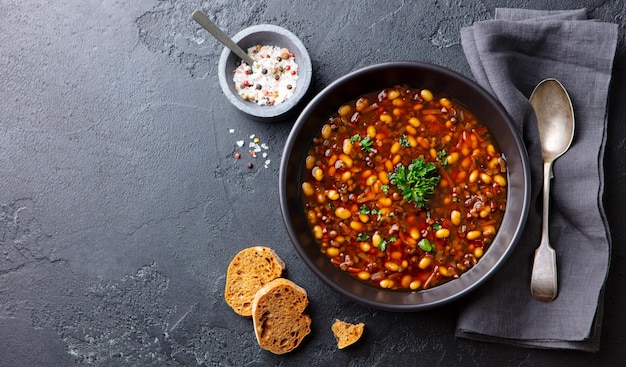 Sopa de frijoles en un tazón negro Fondo gris Espacio de copia Vista superior