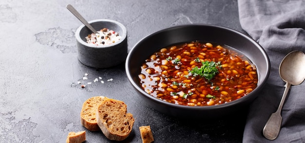 Sopa de frijoles en un tazón negro Fondo negro Copiar espacio