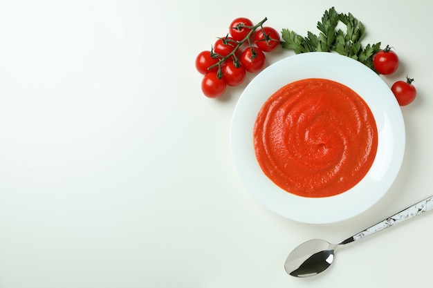 Foto sopa de gazpacho e ingredientes sobre fondo blanco.