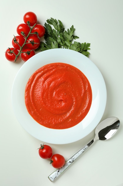 Sopa de gazpacho e ingredientes sobre fondo blanco.