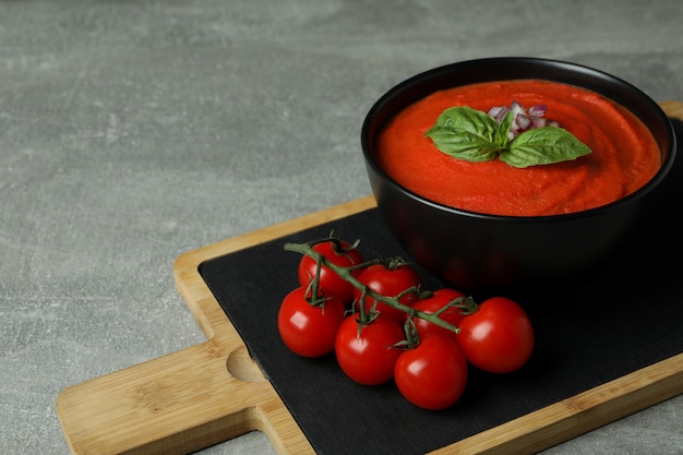 Sopa de gazpacho e ingredientes sobre fondo de textura gris